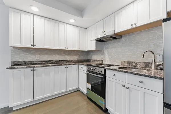 a kitchen with granite countertop white cabinets and stainless steel appliances