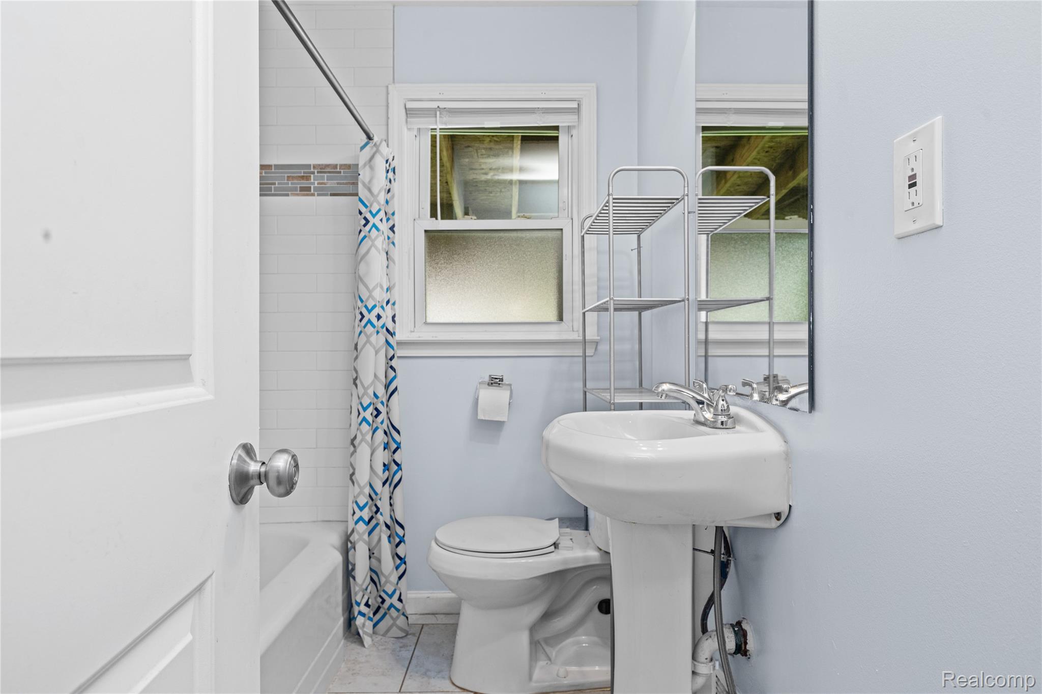 26508 Five Mile Road Redford, MI 48239 - Photo 25 of 41 Bathroom featuring a pedestal sink, white subway tile shower surround with an accent band, a tub, and a window with privacy glass