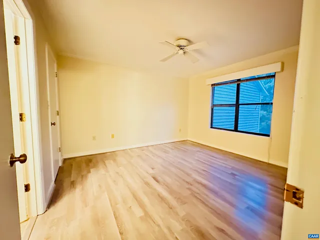 a view of an empty room with wooden floor and a window