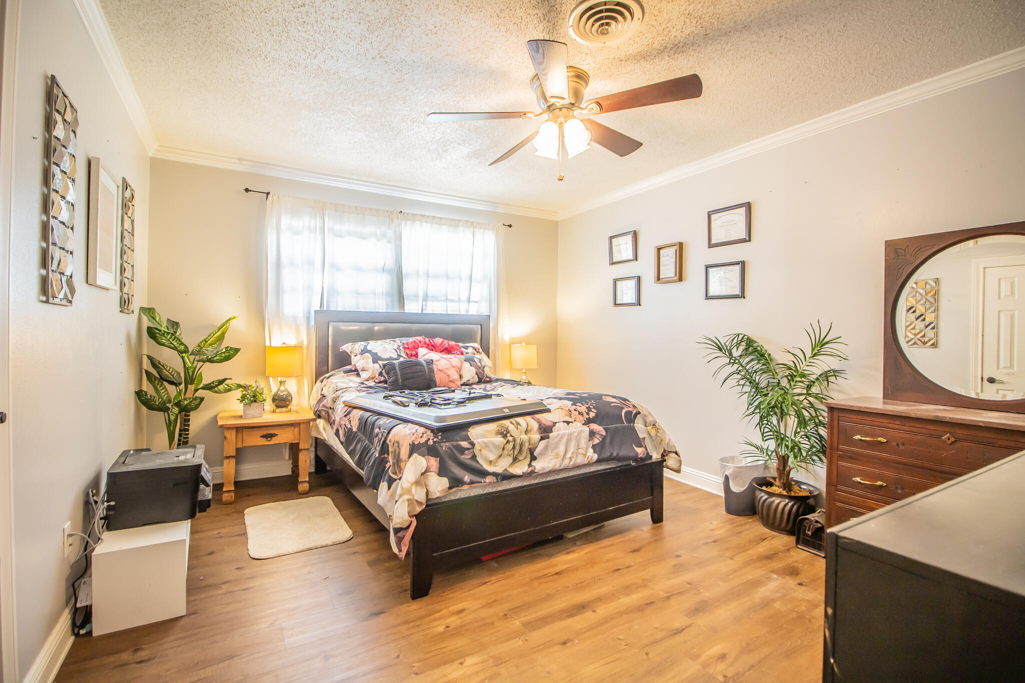 5219 9th Street Lubbock, TX 79416 - Photo 4 of 23 a bedroom with a bed a dresser and potted plants with the wooden floor