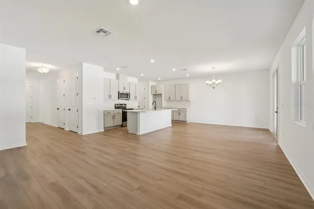 a view of a kitchen with kitchen island stainless steel appliances wooden floor cabinets and a window