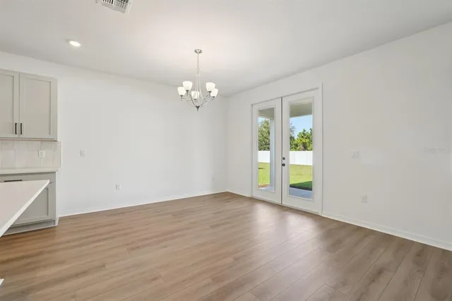 a large kitchen with stainless steel appliances granite countertop a stove a sink a refrigerator and white cabinets with wooden floor