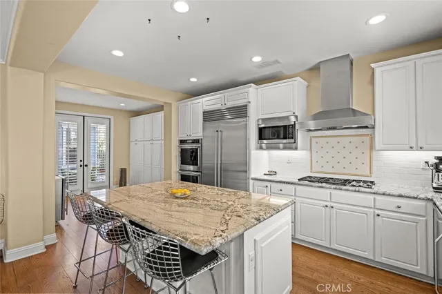 a kitchen with stainless steel appliances a kitchen island hardwood floor sink stove and wooden cabinets