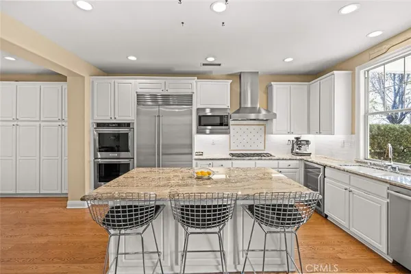 a kitchen with stainless steel appliances kitchen island granite countertop a stove a sink a microwave a refrigerator and cabinets