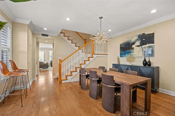 a dining room with wooden floor a chandelier a wooden table and chairs