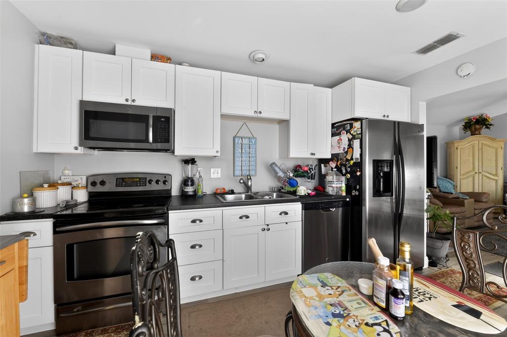 4154 16th Street East, Unit 15 Ellenton, FL 34222 - Photo 14 of 31 a kitchen with granite countertop a refrigerator stove and white cabinets