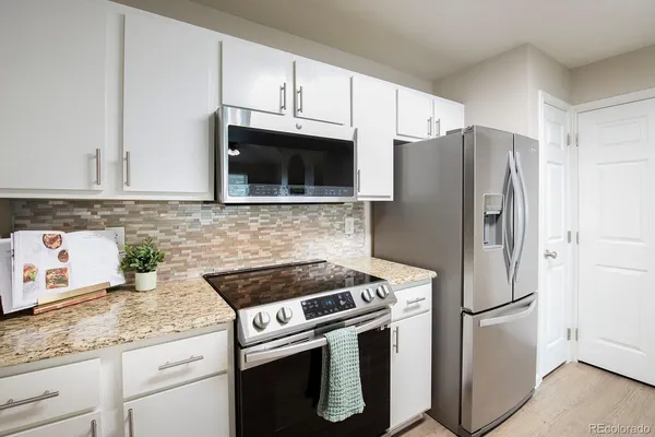 a kitchen with granite countertop a refrigerator stove and microwave