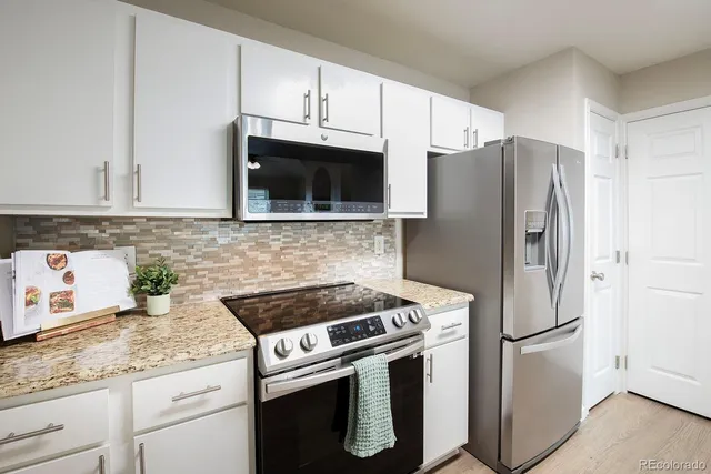 a kitchen with granite countertop a refrigerator stove and microwave