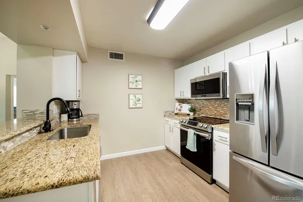 a kitchen with stainless steel appliances granite countertop a refrigerator stove and sink