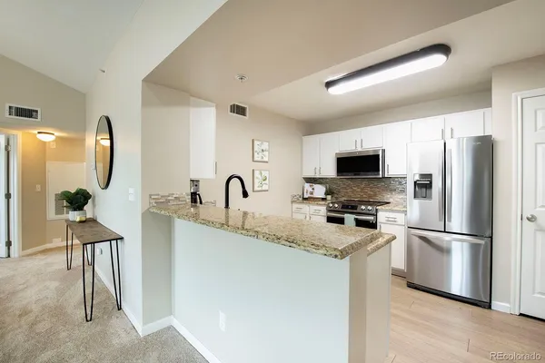 a kitchen with stainless steel appliances granite countertop a refrigerator sink and stove