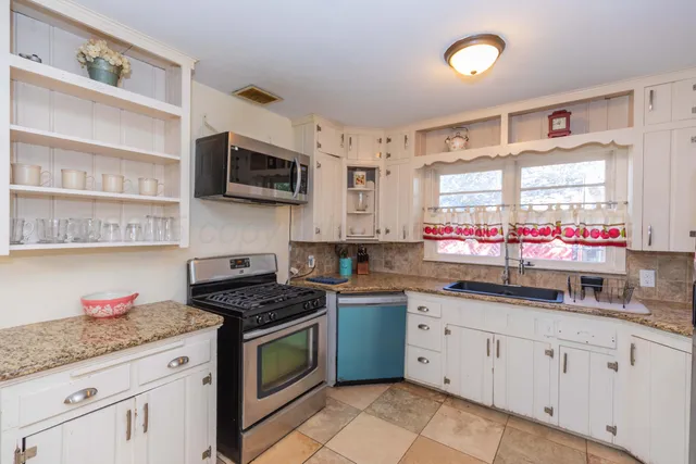 a kitchen with granite countertop stainless steel appliances a sink dishwasher a stove and a microwave