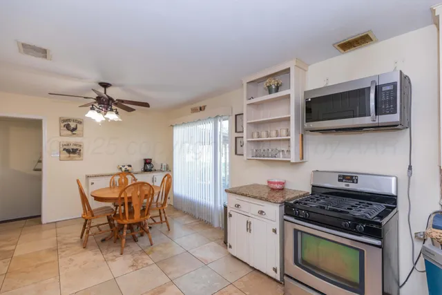 a kitchen with stainless steel appliances kitchen island granite countertop a stove top oven a sink a dining table and chairs