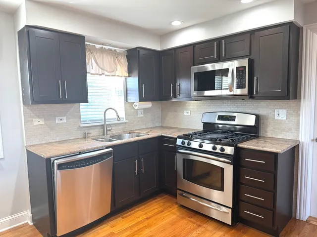 a kitchen with stainless steel appliances a sink a stove a microwave a sink and cabinets