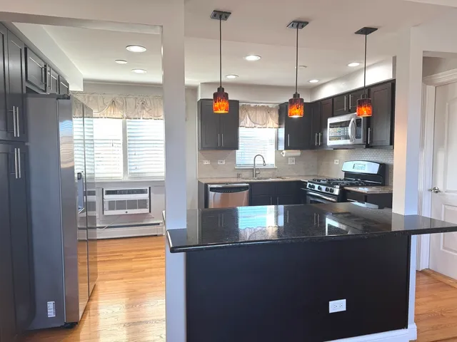 a kitchen with stainless steel appliances granite countertop a sink a stove and a refrigerator