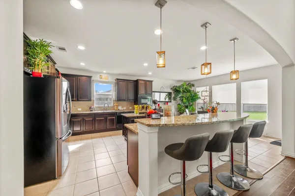 a kitchen with stainless steel appliances kitchen island granite countertop a refrigerator a sink and a stove