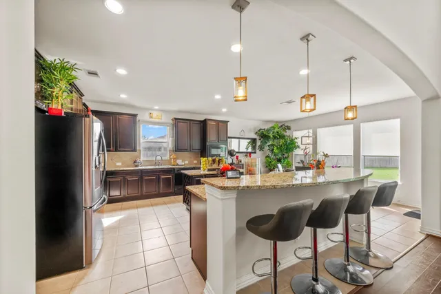 a kitchen with stainless steel appliances kitchen island granite countertop a refrigerator a sink and a stove