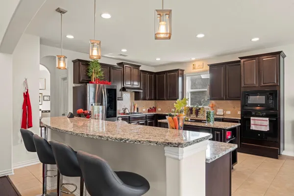 a kitchen with stainless steel appliances kitchen island granite countertop a refrigerator and a stove top oven