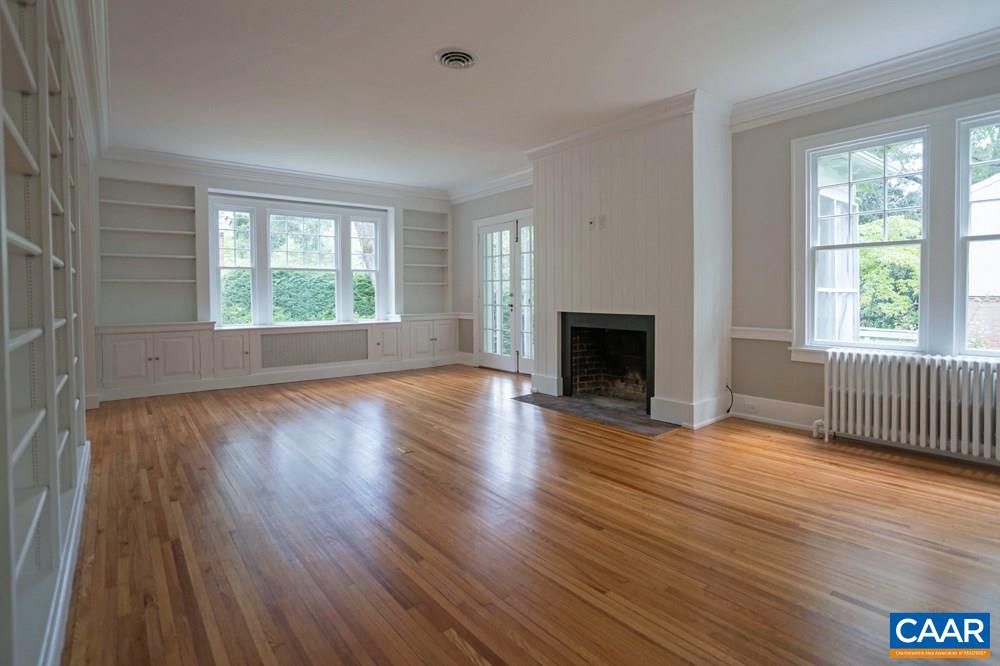 1930 Thomson Road Charlottesville, VA 22903 - Photo 5 of 35 an empty room with wooden floor fireplace and windows