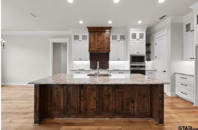 a kitchen with kitchen island granite countertop a table chairs refrigerator and cabinets