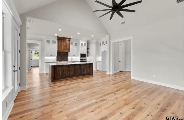 a view of a kitchen with kitchen island a sink wooden floor and a ceiling fan