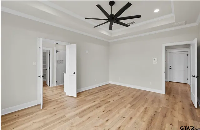 an empty room with wooden floor and ceiling fan