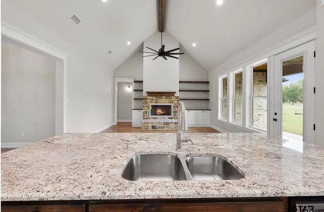 a kitchen with a sink granite counter tops and a view of living room