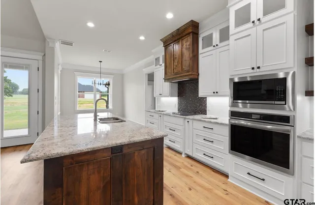 a kitchen with stainless steel appliances granite countertop a stove a sink and a microwave