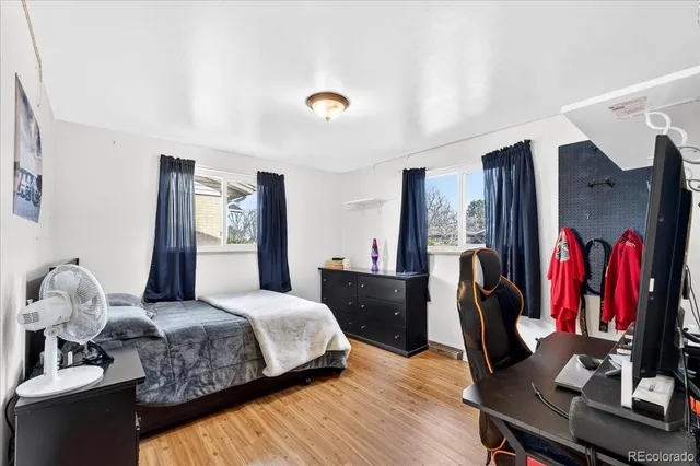 a bedroom with a bed and dresser with wooden floor