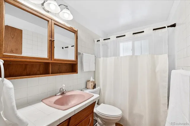 a bathroom with a sink toilet a mirror and shower curtain