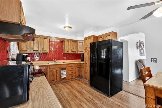a kitchen with stainless steel appliances granite countertop a refrigerator a stove and a sink with wooden floor