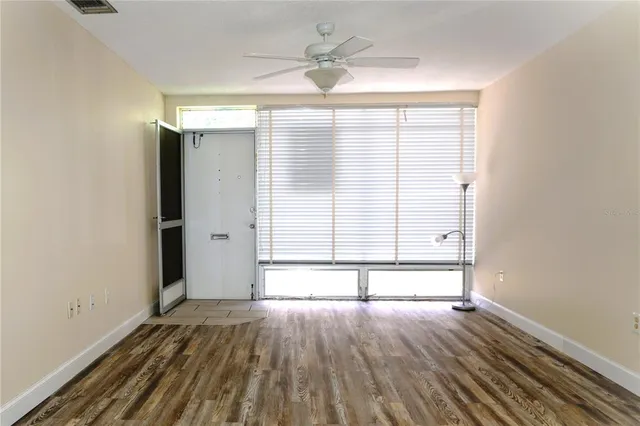 an empty room with wooden floor and windows