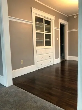 an empty room with wooden floor and cabinet