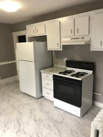 a kitchen with stainless steel appliances granite countertop a refrigerator stove a sink and white cabinets