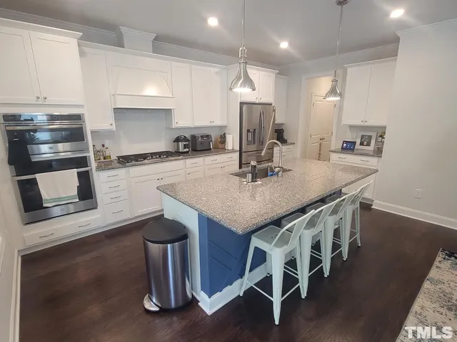 a kitchen with stainless steel appliances granite countertop a kitchen island hardwood floor and a sink