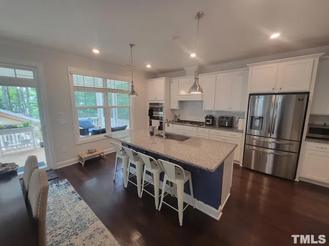 a kitchen with stainless steel appliances granite countertop a stove a refrigerator a sink a dining table and chairs