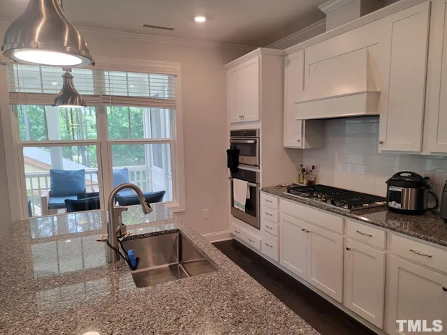a kitchen with granite countertop a stove a sink and a white cabinets