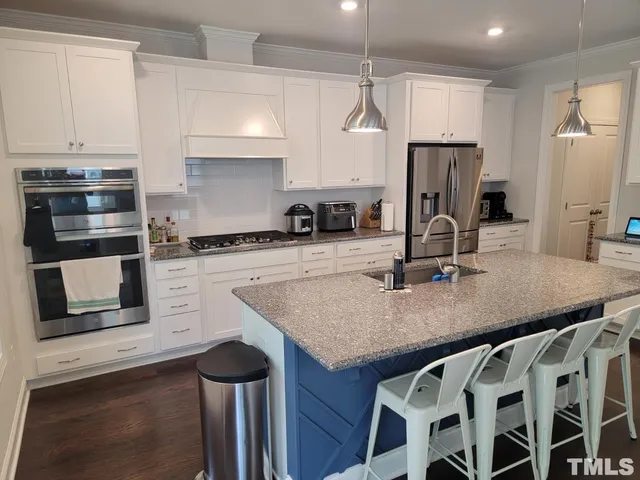 a kitchen with stainless steel appliances granite countertop a sink a stove and a refrigerator