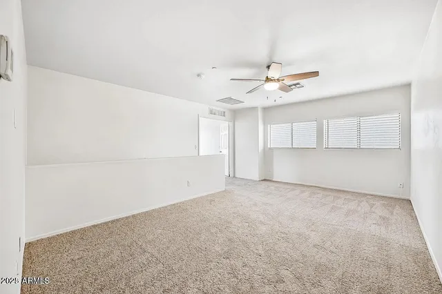 an empty room with ceiling fan and window