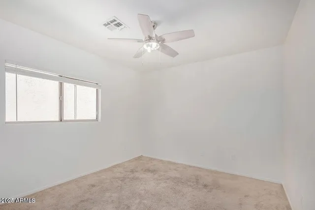 an empty room with a window and a fan