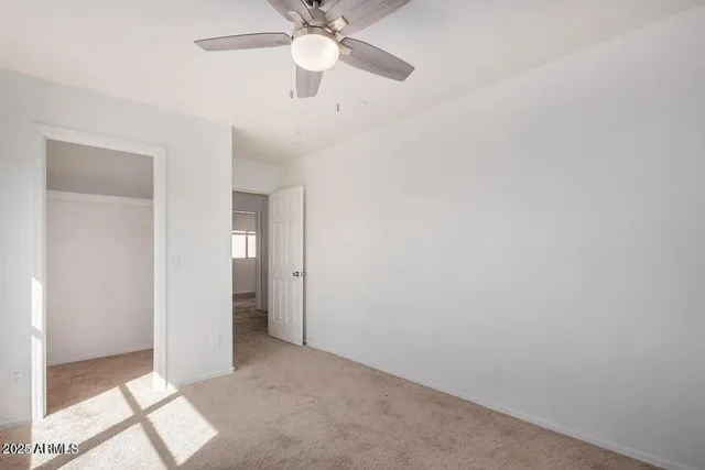 an empty room with a ceiling fan and a window
