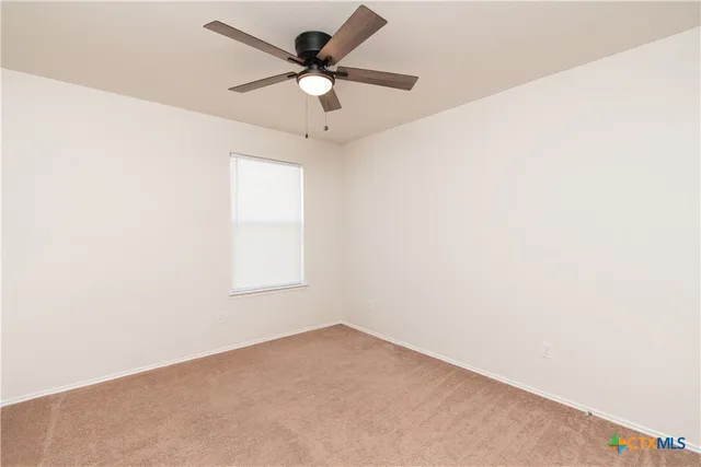 an empty room with a window and a fan