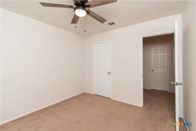 an empty room with a ceiling fan and a window