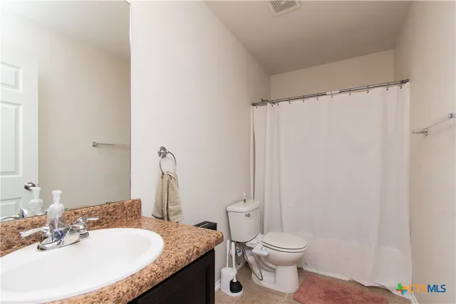 a bathroom with a granite countertop sink toilet and a mirror