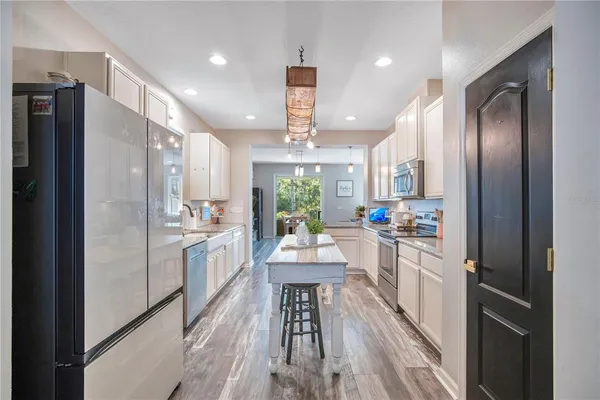 an open kitchen with kitchen island wooden floor center island and stainless steel appliances