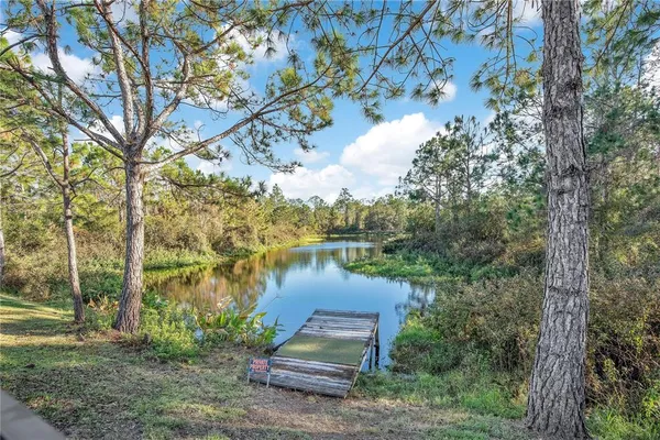 a view of a lake with a yard and large trees