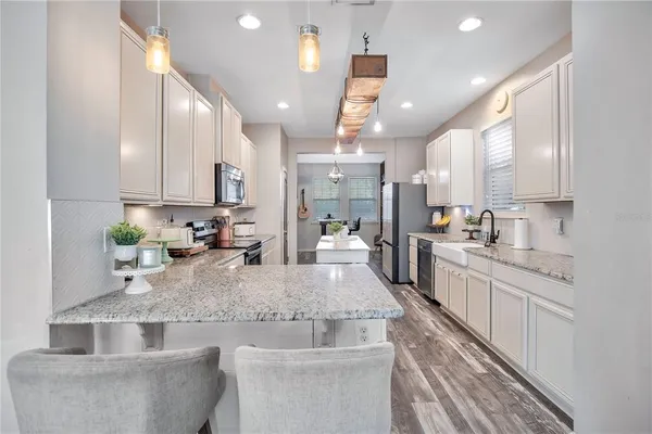 a large kitchen with kitchen island a large counter top stainless steel appliances and cabinets