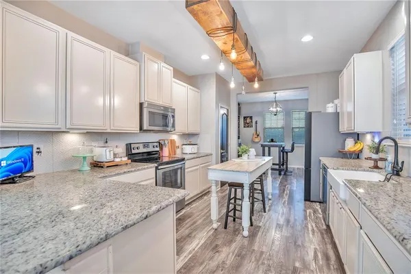 a kitchen with stainless steel appliances granite countertop a stove top oven a sink dishwasher a dining table and chairs with wooden floor