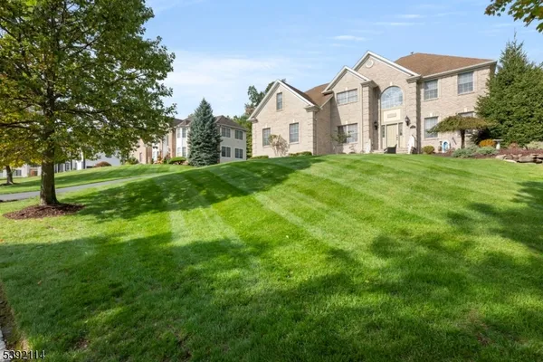 a view of a white house with a big yard and large trees