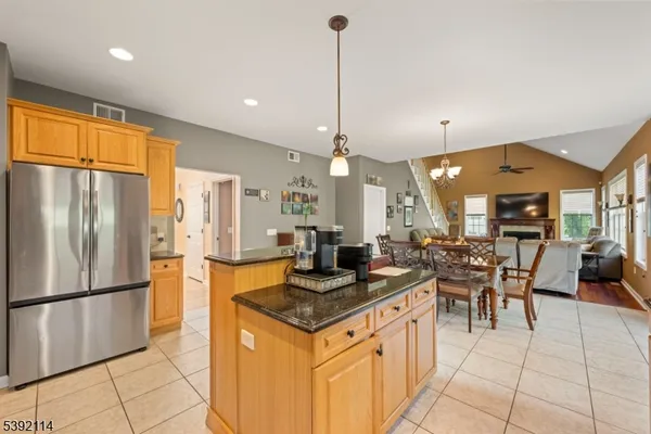 a kitchen with stainless steel appliances granite countertop a refrigerator a sink dishwasher a dining table and chairs with wooden floor