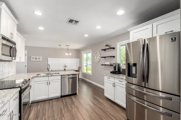 a kitchen with stainless steel appliances a refrigerator a sink and white cabinets